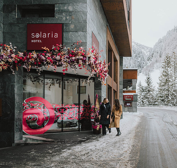 Eingangsbereich des 4-Sterne-Hotels Solaria in Ischgl mit winterlicher Dekoration und Blumenarrangements.
