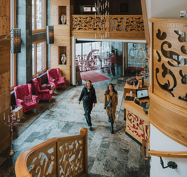 Eleganter Eingangsbereich des 4-Sterne-Hotels Solaria in Ischgl mit luxuriösen roten Sesseln und dekorativem Holzdesign.